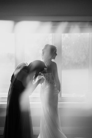 Artistic black and white silhouettes of wedding couple by window creating dramatic contrast.