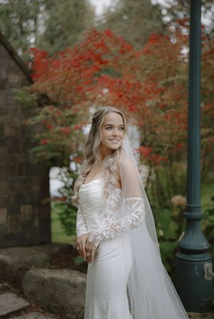 Wedding dress with lace details photographed against autumn foliage with red maple leaves.