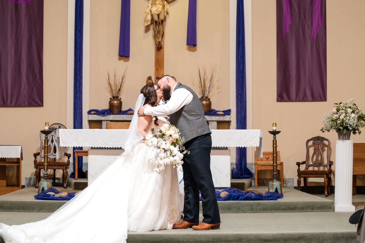 Wedding ceremony taking place in church sanctuary with purple and blue decorative banners.