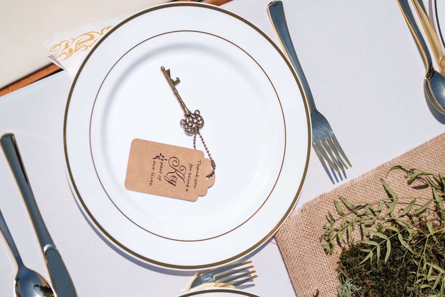 Elegant place setting with vintage key on white plate and rustic paper tag.