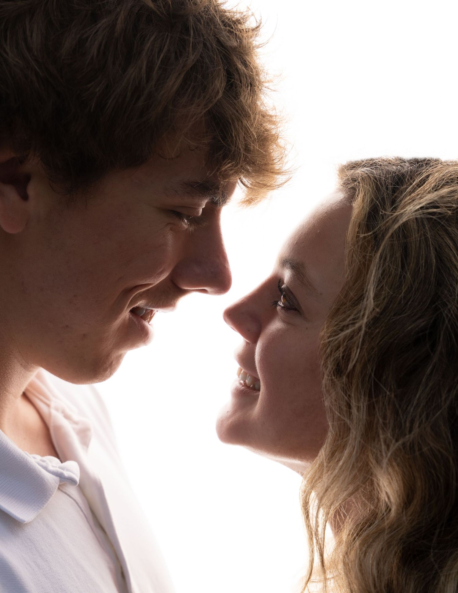 A romantic couple gazing lovingly at each other in an intimate close-up portrait with soft lighting.