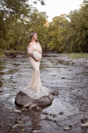 outdoor maternity session mom in lace dress standing on a rock in the creek etobicoke