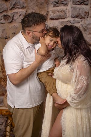 Boho maternity session parents kissing toddler