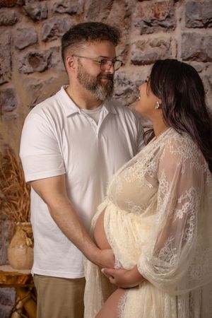 maternity photo with couple looking at each other and holding belly