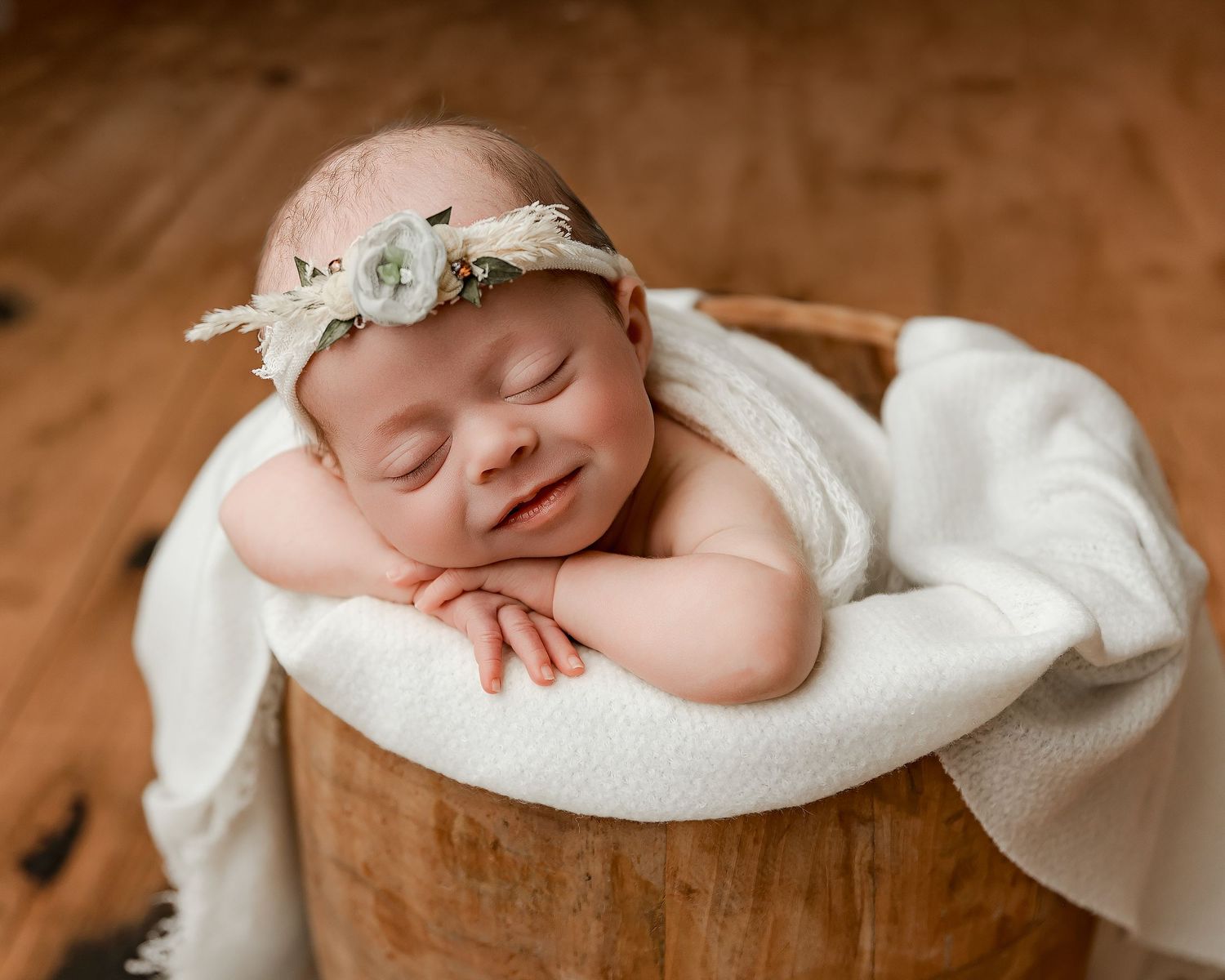 Sleeping newborn in cream outfit on textured blanket.