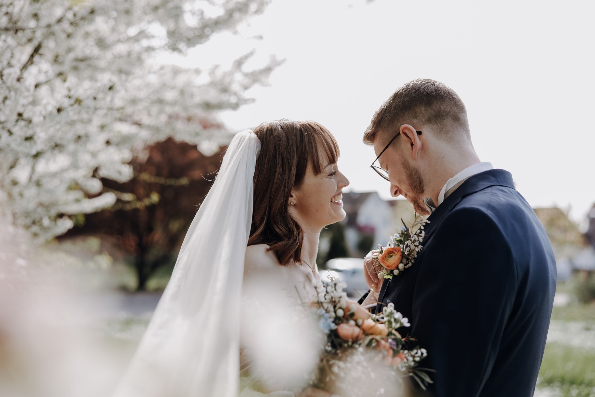 Romantic spring wedding portrait with cherry blossoms in soft focus.