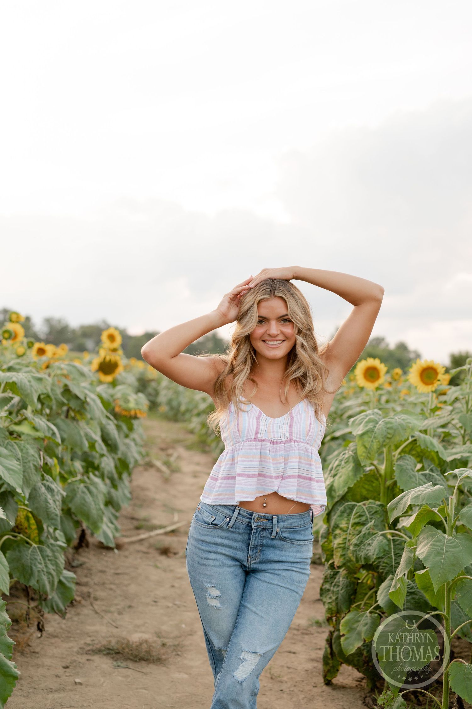A casual summer portrait in a sunflower field with distressed jeans and a cropped top.