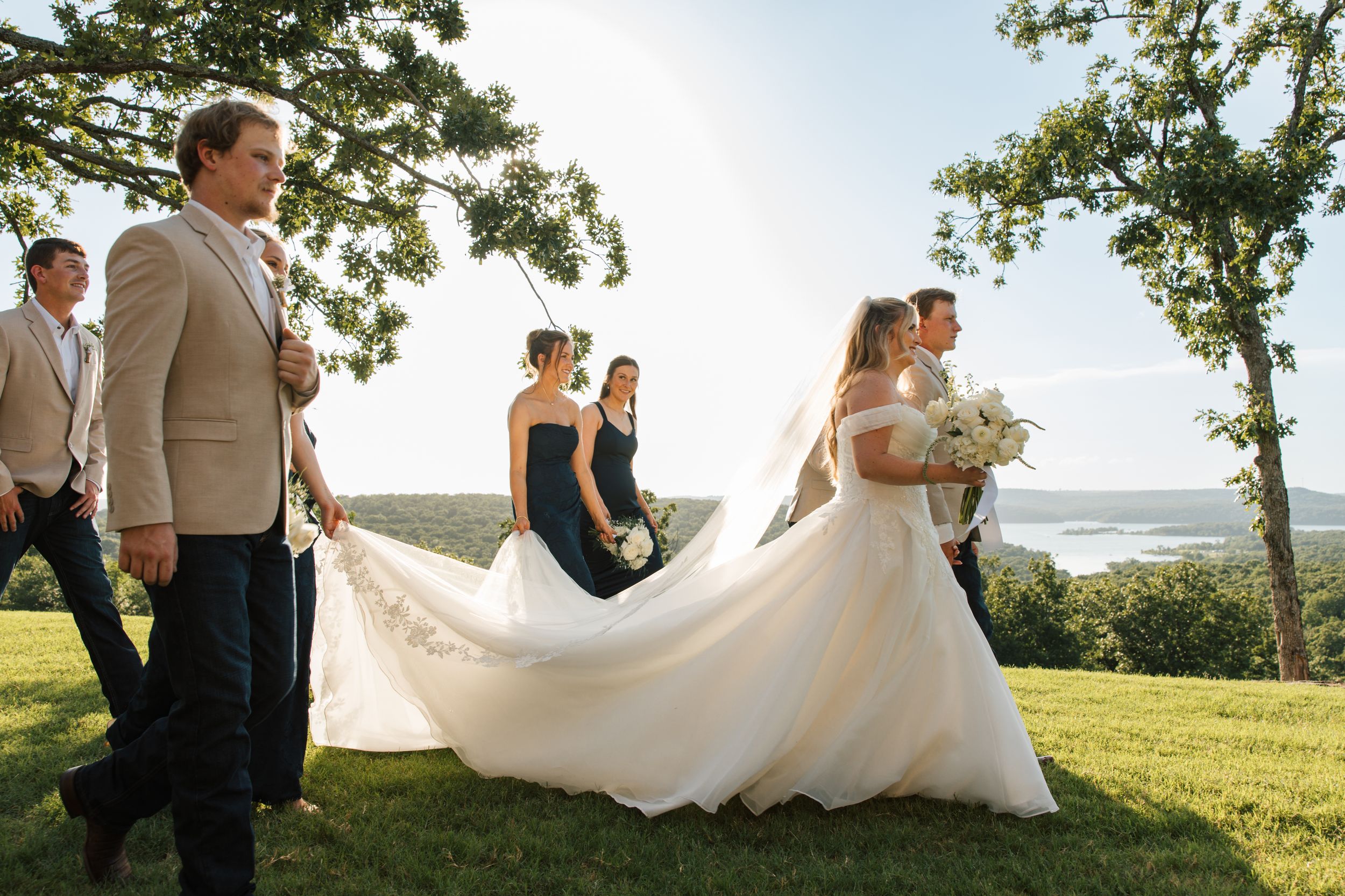 A wedding party poses with the bride and groom on the lawn at 1684 Wedding Venue in Cookson, Oklahoma for a documentary style photo.