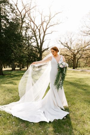 A bride tosses her veil during her wedding portraits in a park in Abilene, Kansas on her wedding day.