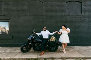 A couple pose with the groom on his motorcycle on their elopement wedding day in Tulsa, Oklahoma. Courthouse wedding.