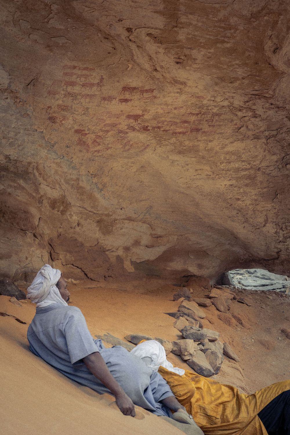 Natural rock cave formation with sandy floor and weathered stone walls.