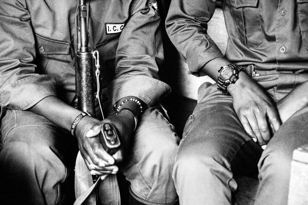 Close-up of military personnel holding rifles while seated, shown in black and white.