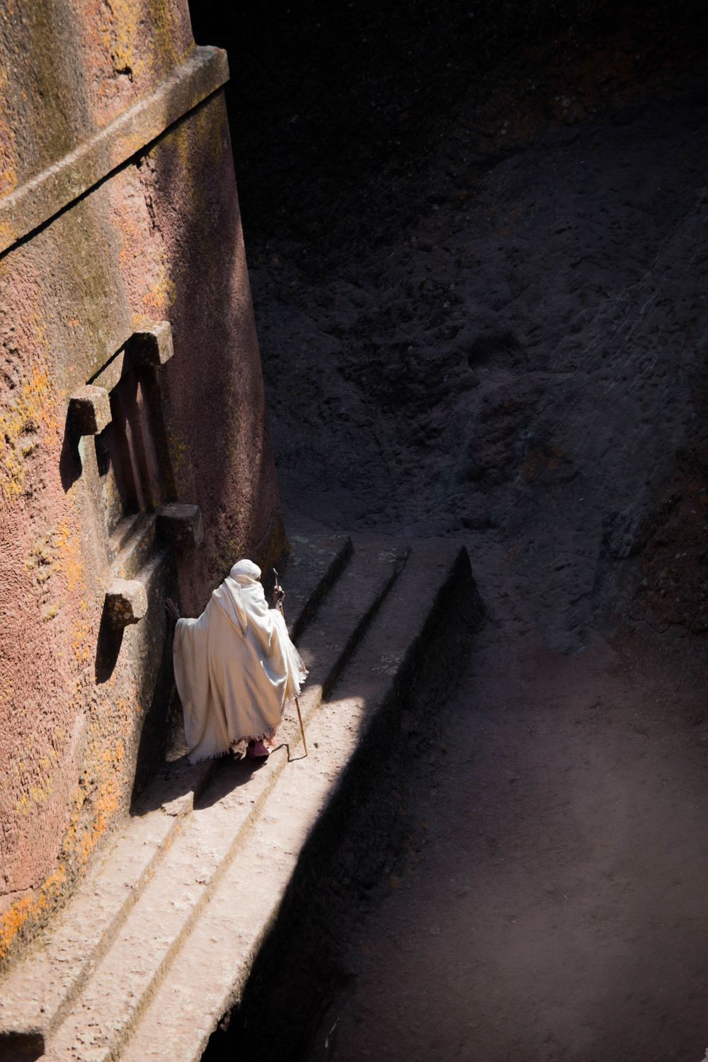 Dramatic shadow and light play in a narrow stone passageway.