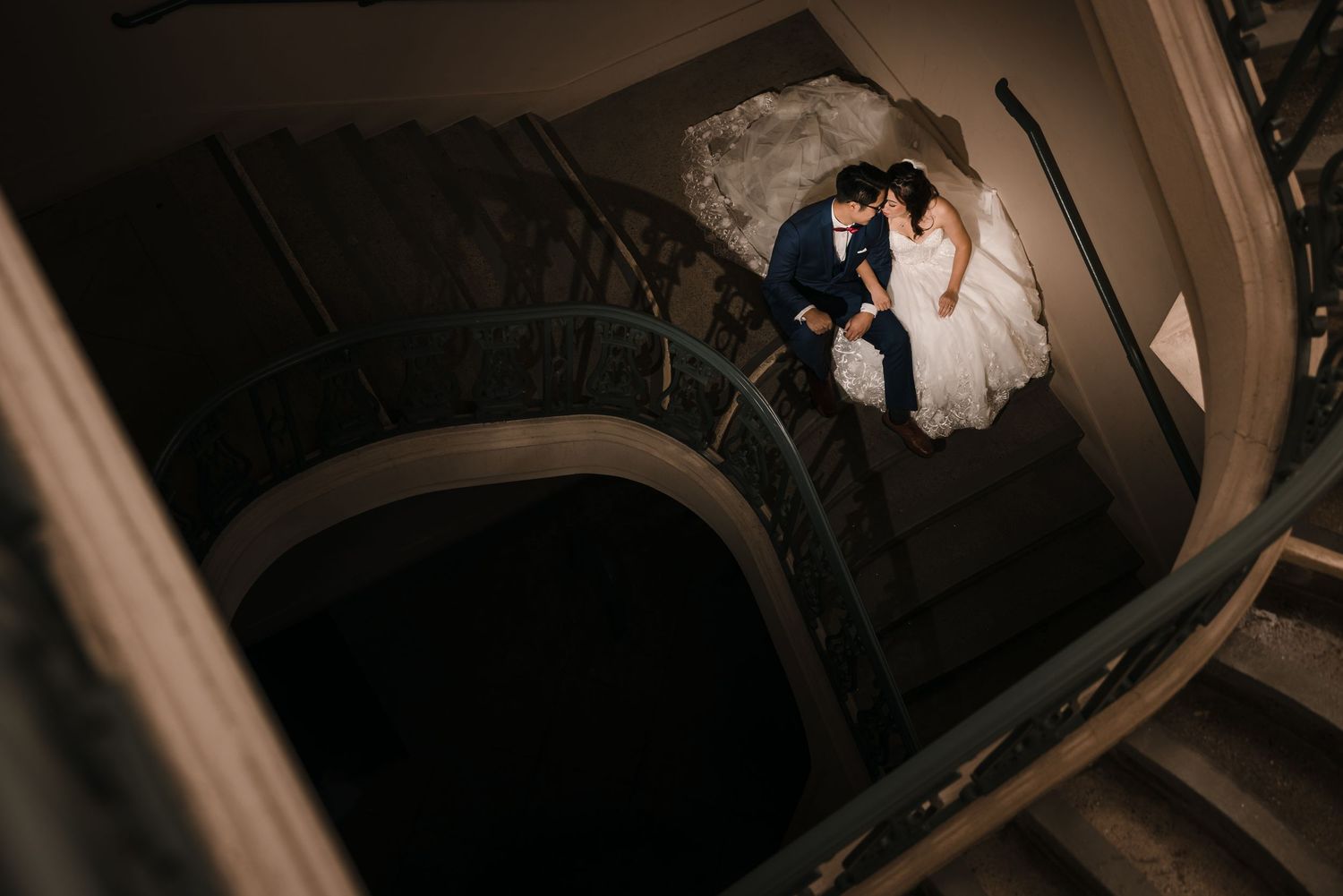 A creative overhead shot of a couple on a spiral staircase creating dramatic shadows and lines.