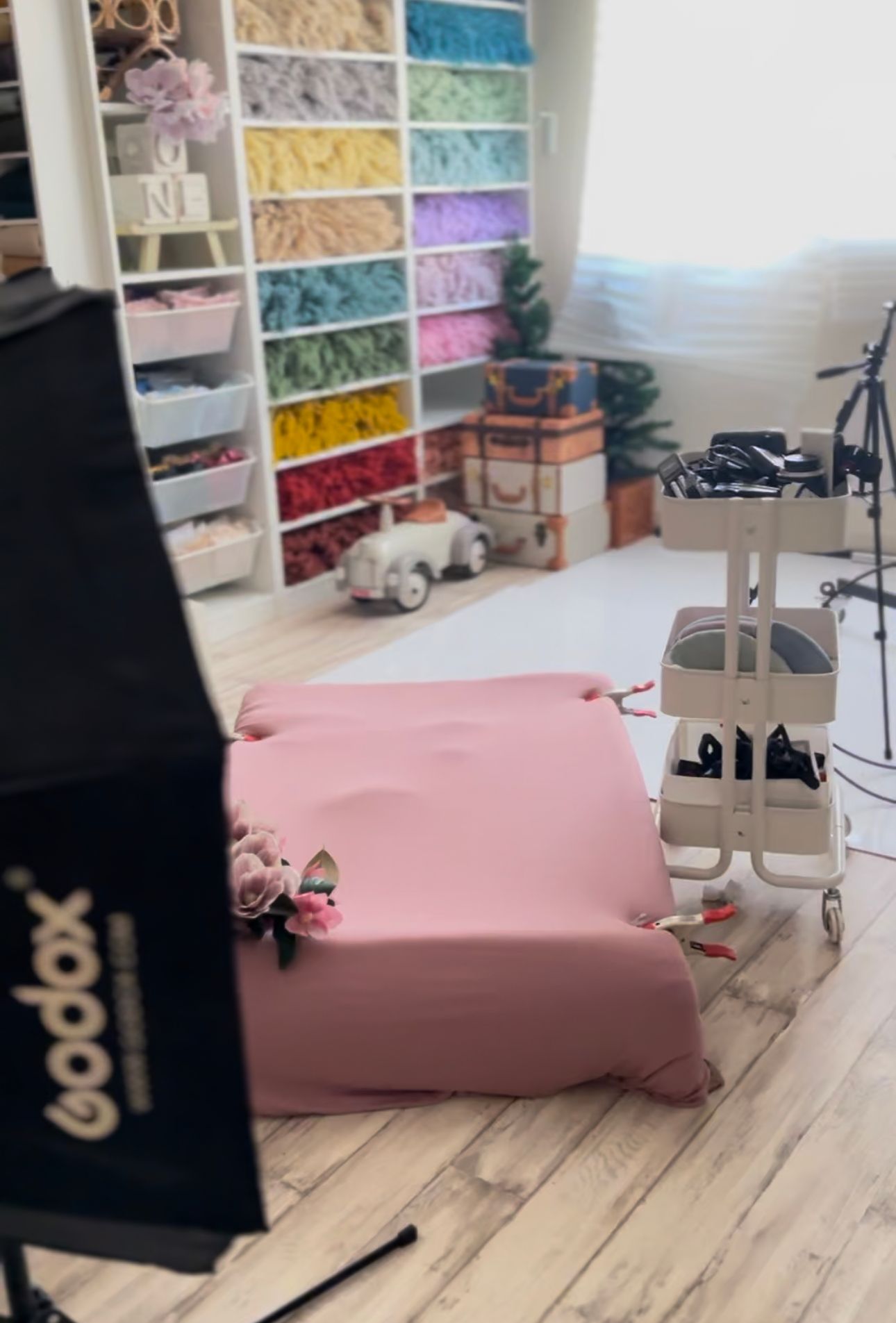 Photography studio setup with colorful fabric storage shelves and equipment.