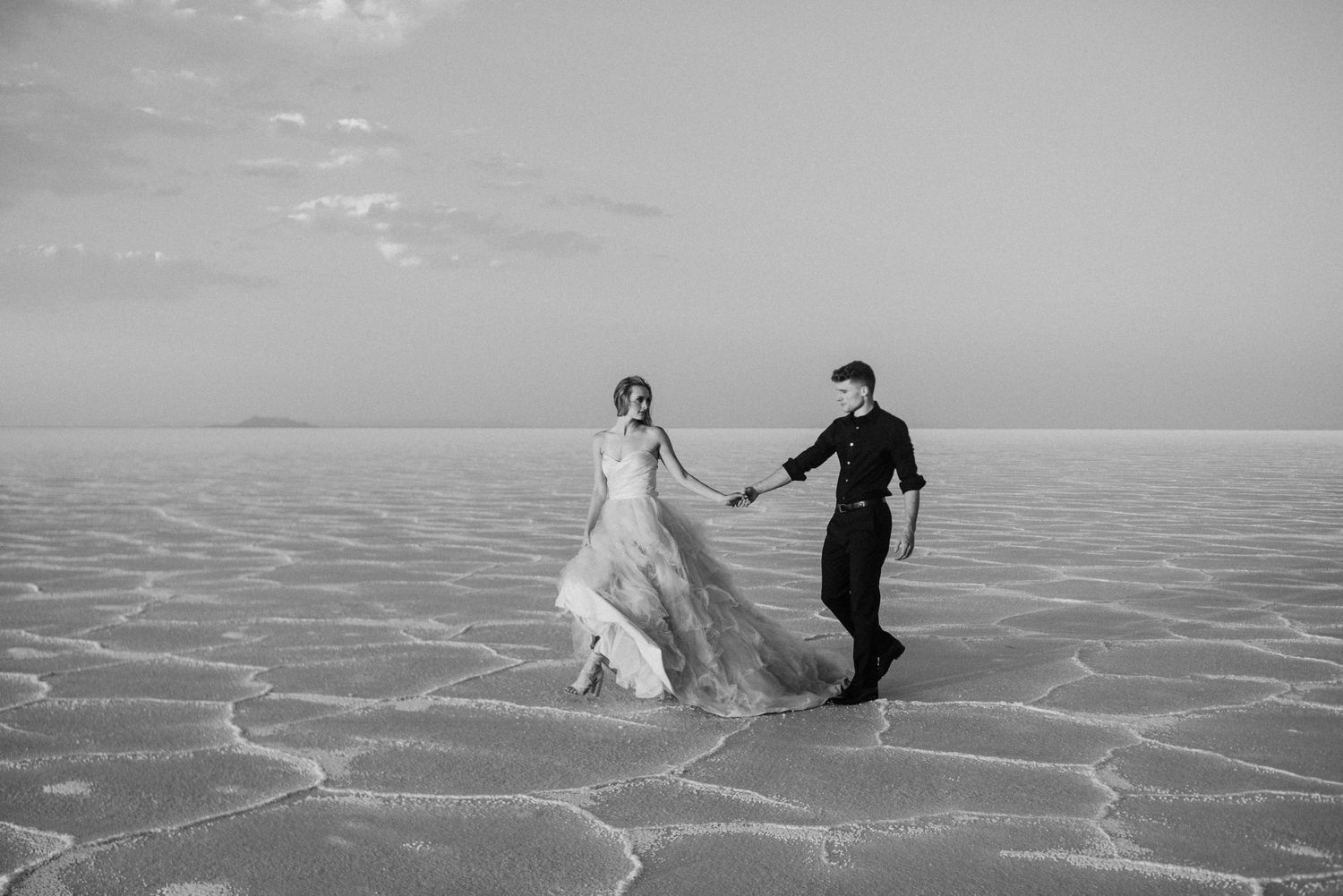 A couple in wedding attire dances together on the stark white patterns of the Bonneville Salt Flats in Utah.