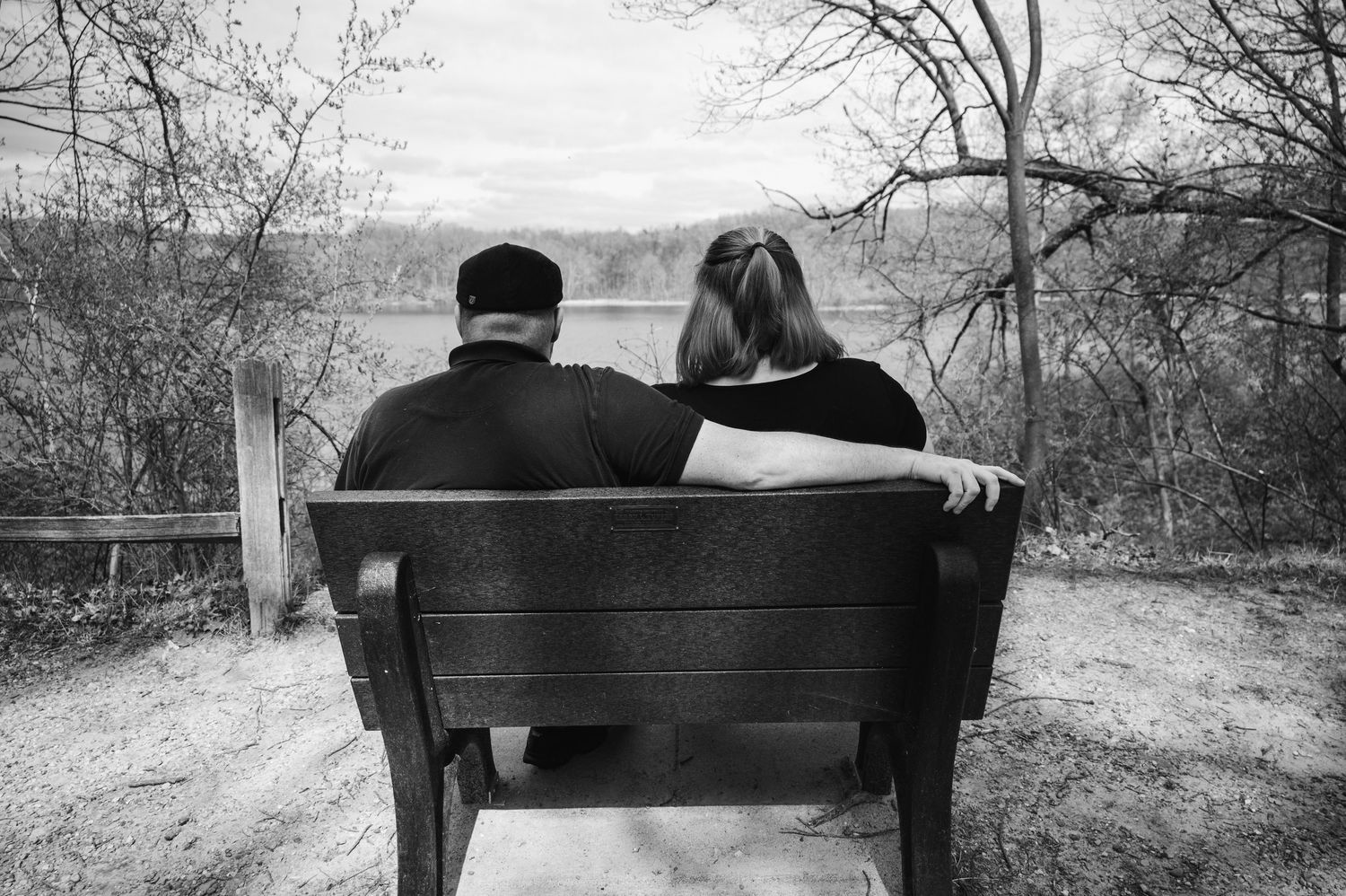 Couple sharing a playful moment in a fall field with orange trees in the background.