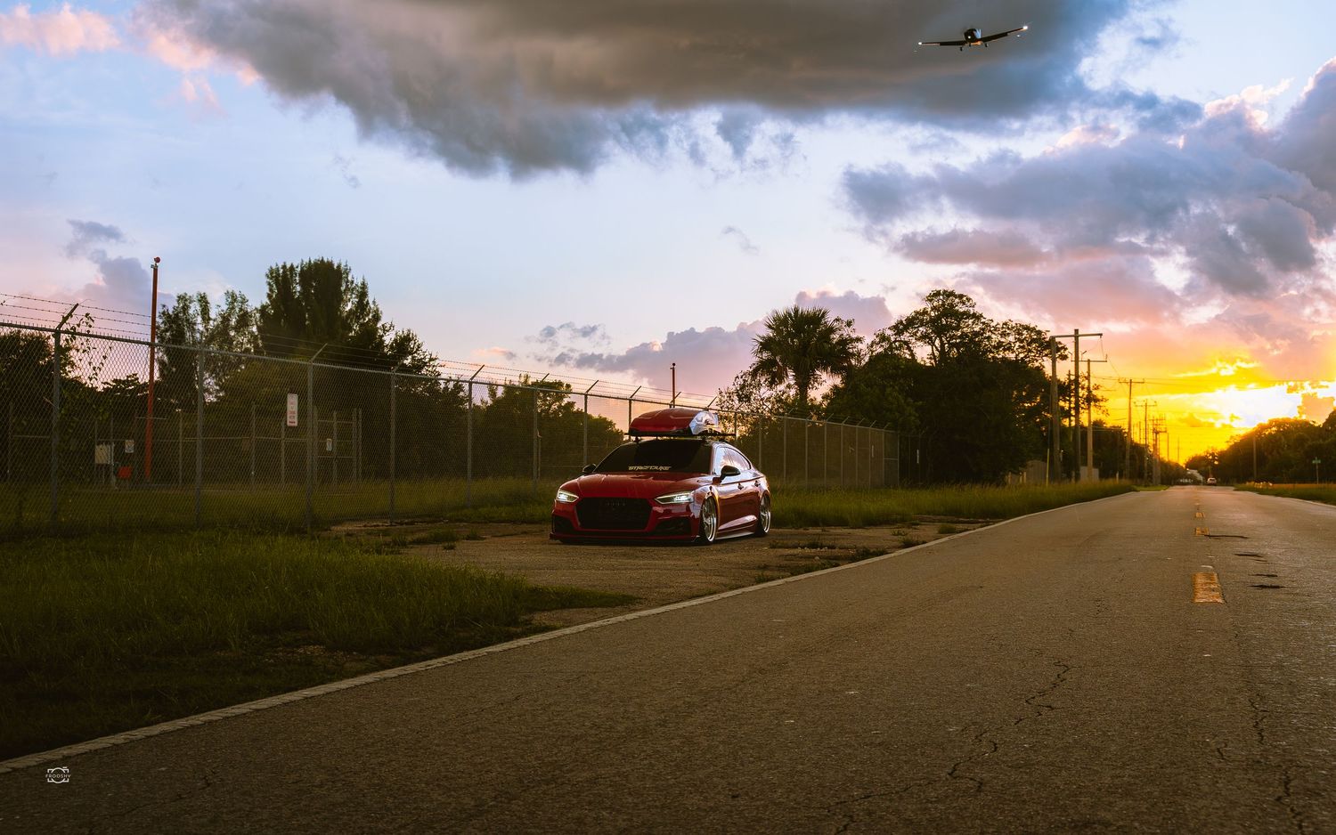 Panoramic skyline view at sunset with dramatic clouds and distant airplane silhouette.