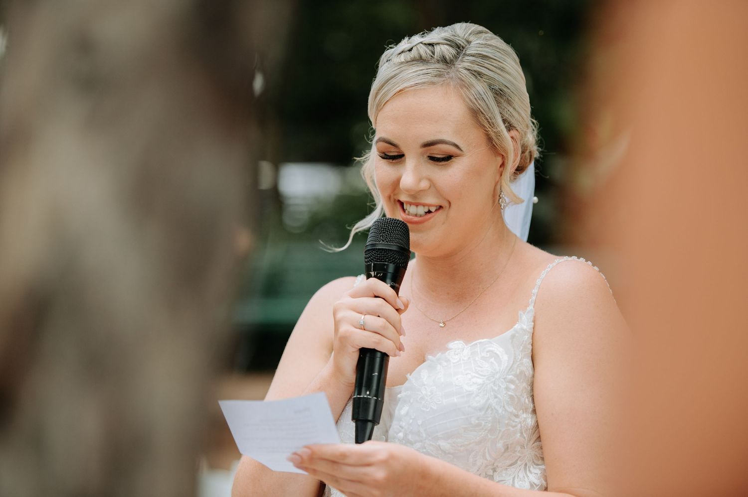 A joyful moment during a wedding speech with someone in a lace dress holding a microphone.