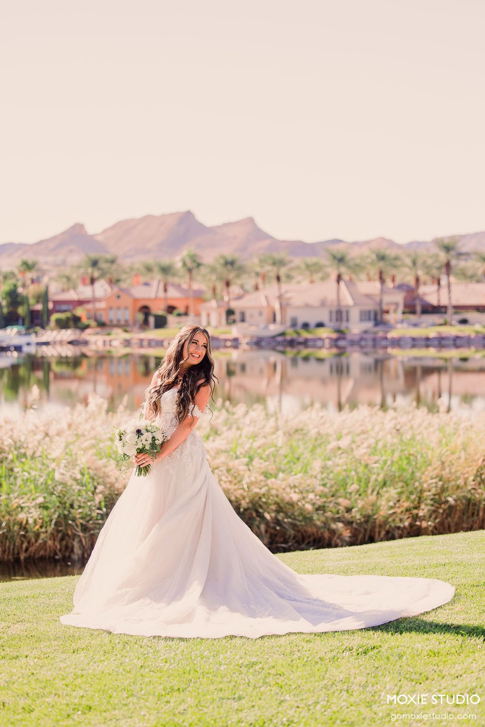 A scenic lakeside wedding photo series showing a flowing white gown against mountains and water in the background.