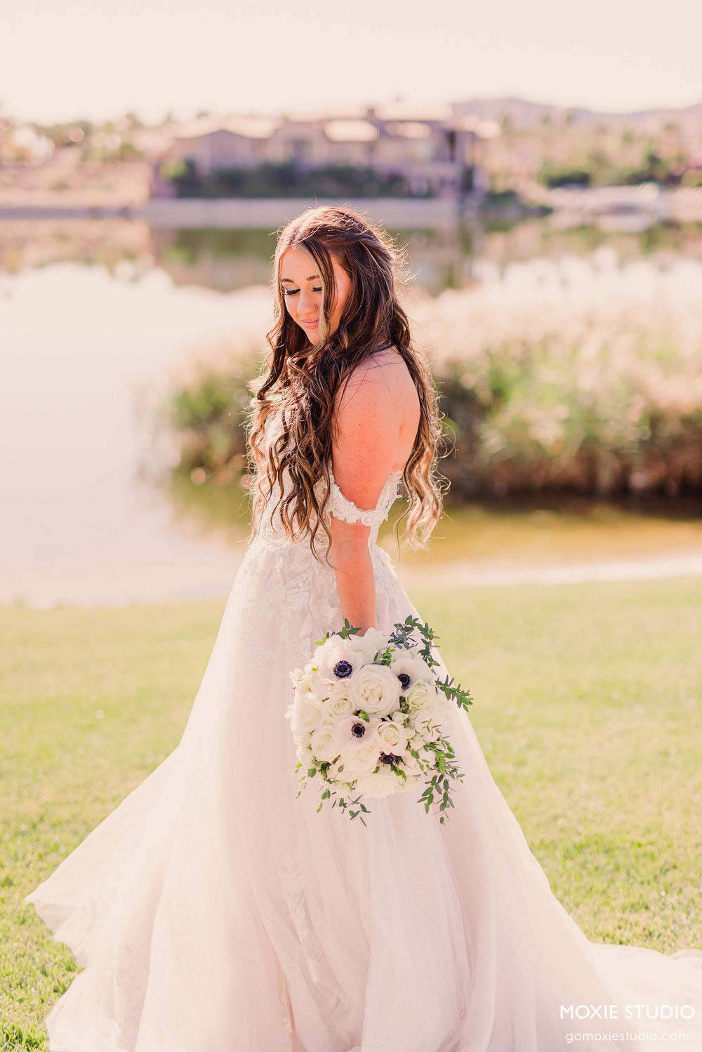 A bride in a flowing white wedding dress twirls gracefully in a sunlit outdoor garden setting.