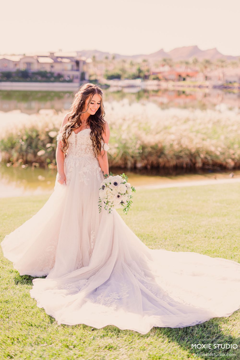 A bride in a flowing white wedding dress twirls gracefully in a scenic outdoor setting with mountains in the background.