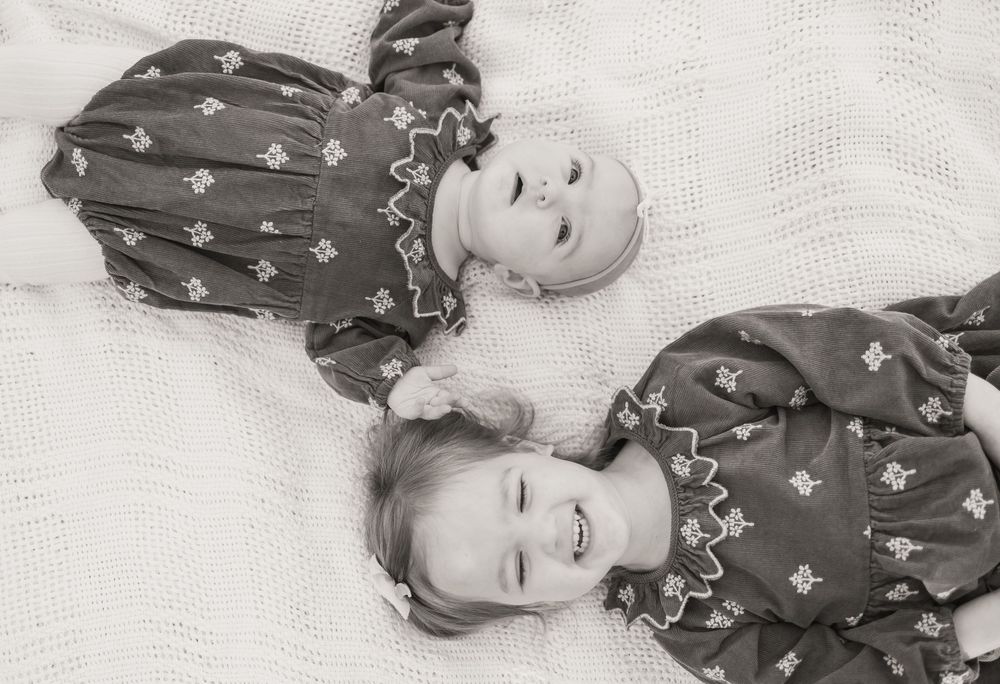 A series of black and white photos showing a baby in a floral dress making different playful expressions.
