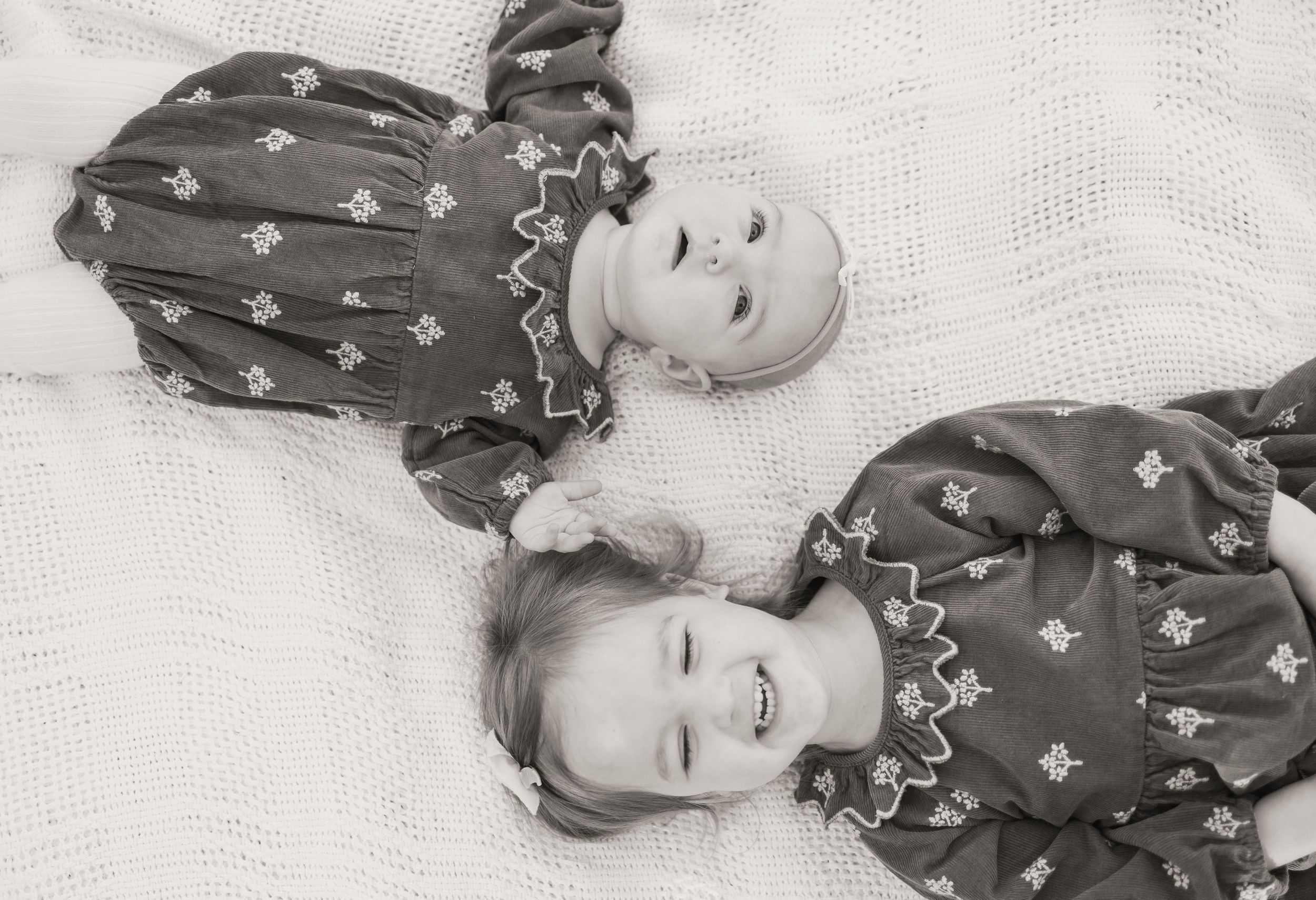 A series of black and white photos showing a baby in a floral dress making different playful expressions.