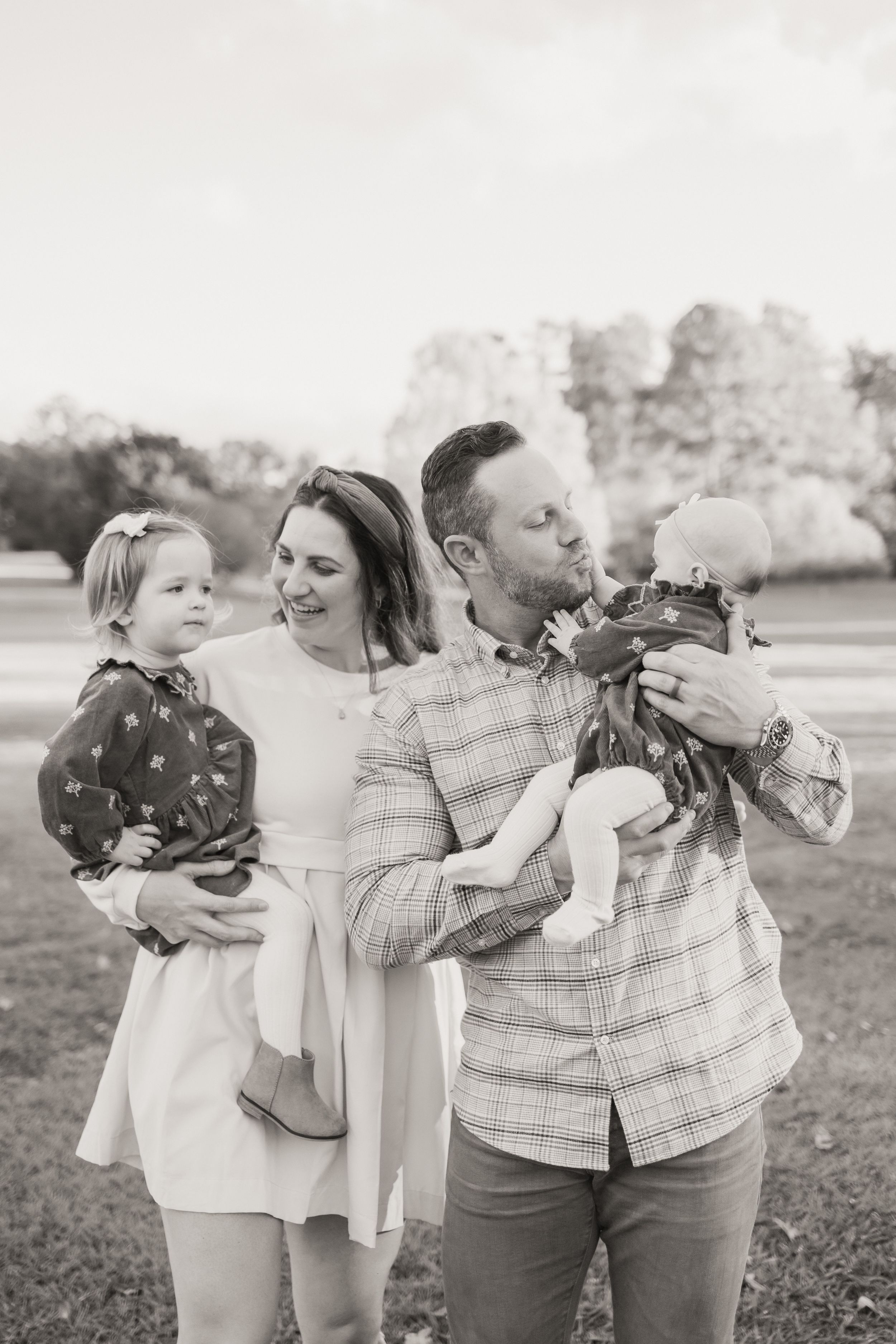 A series of black and white candid family photos showing intimate moments between parents and children outdoors.