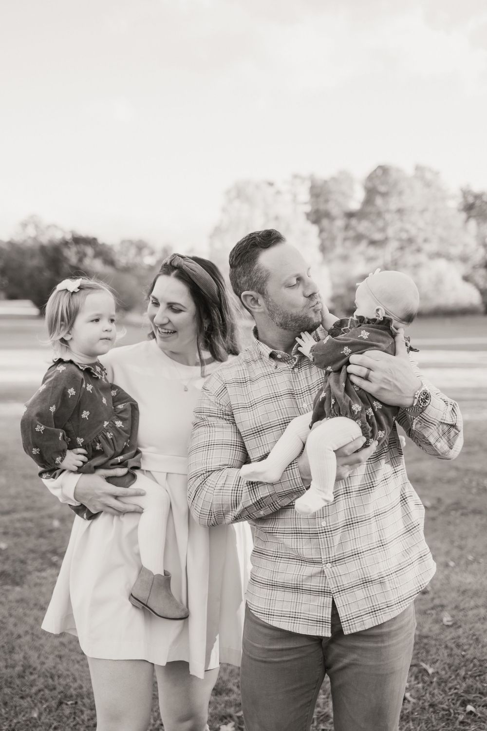 A series of black and white candid family photos showing intimate moments between parents and children outdoors.