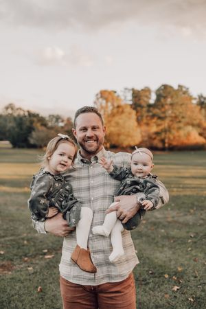 Family smiles together during outdoor autumn portrait session wearing coordinated casual attire.