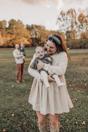 A series of outdoor autumn photos showing tender moments between parent and child in cream colored outfits on grassy field.