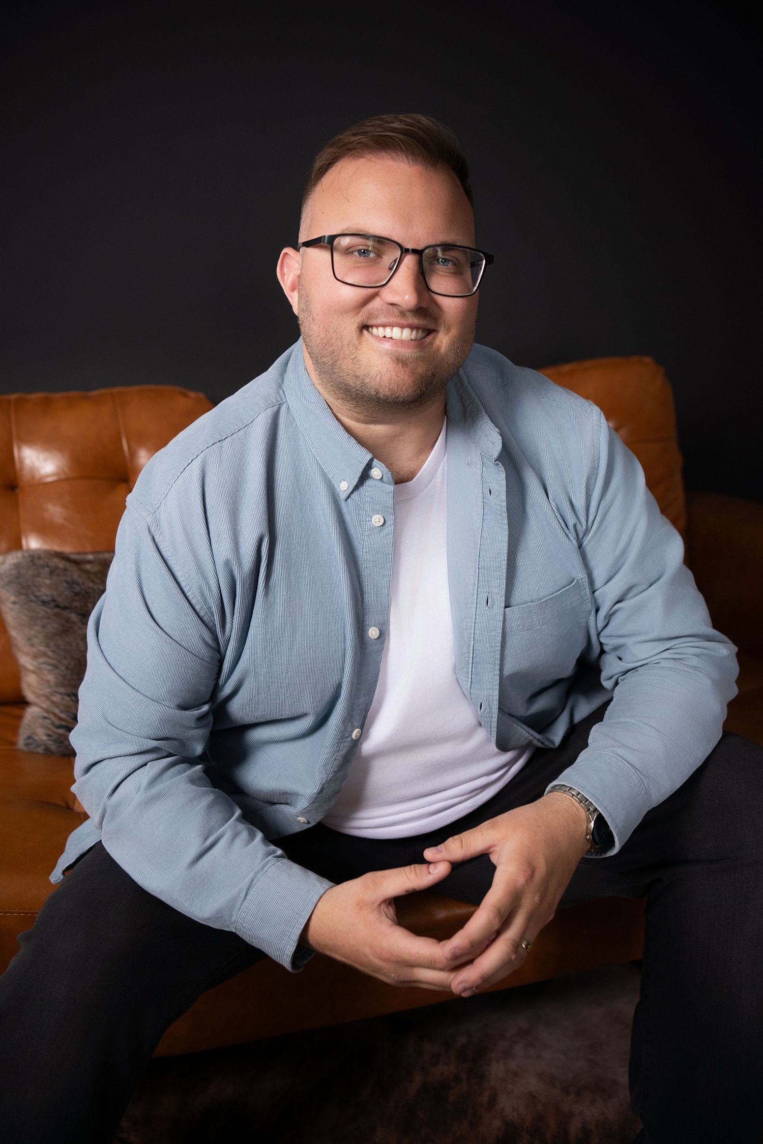 Branding portrait on brown leather couch with green plants in background in downtown Columbia photography studio.