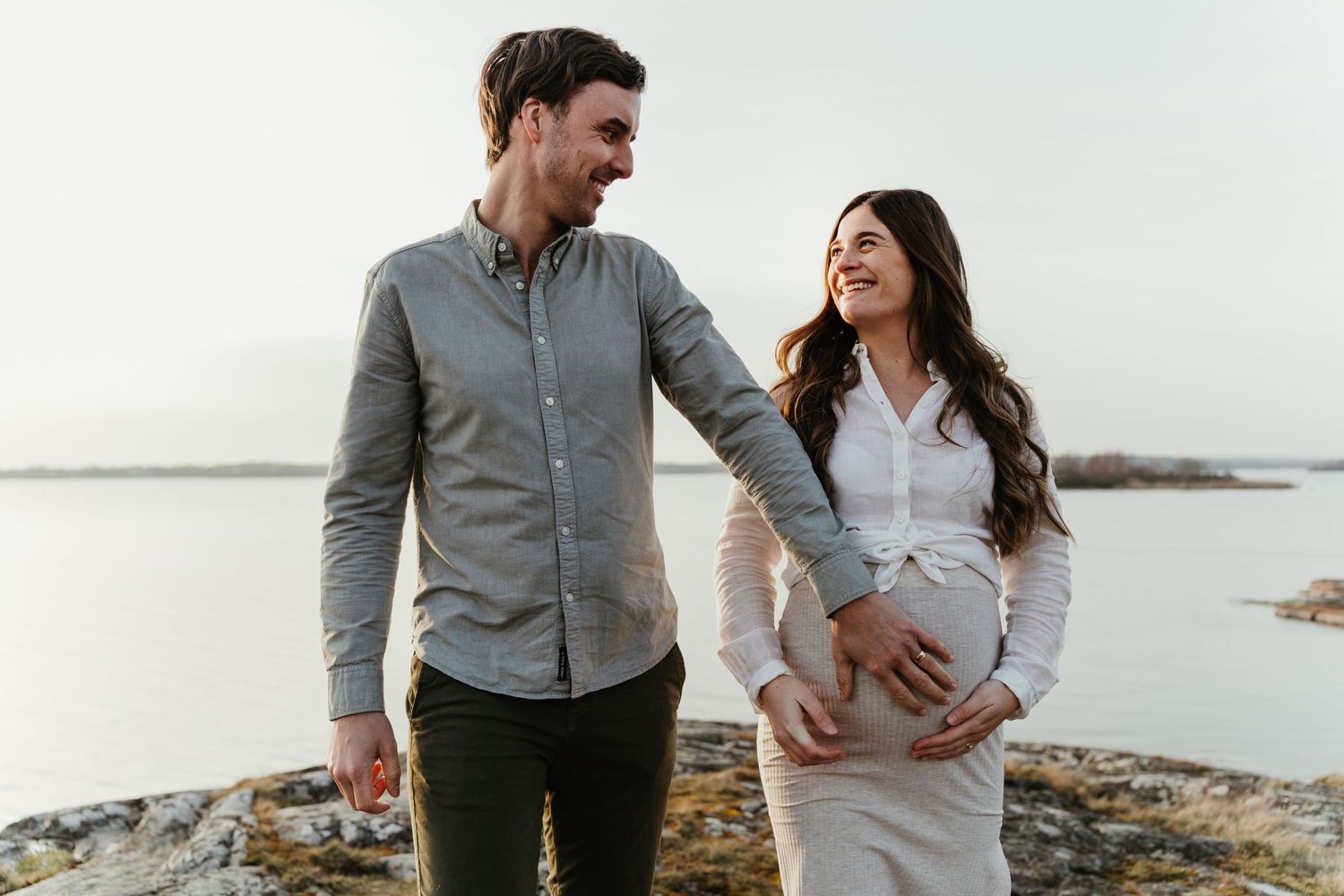 Expectant couple shares a tender moment by the ocean.