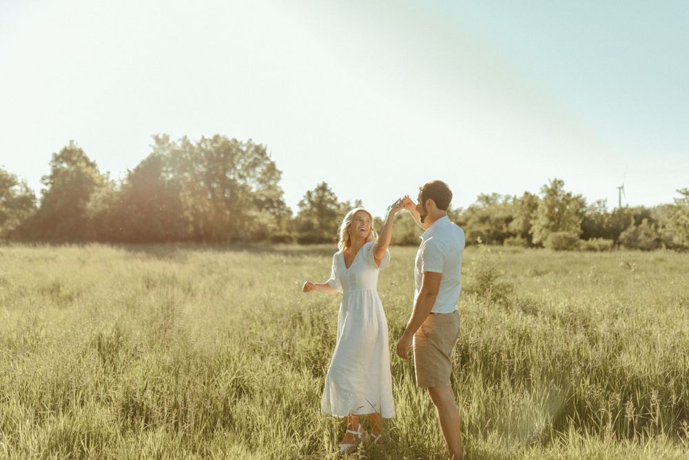 A couple smiling together in a golden meadow during sunset.