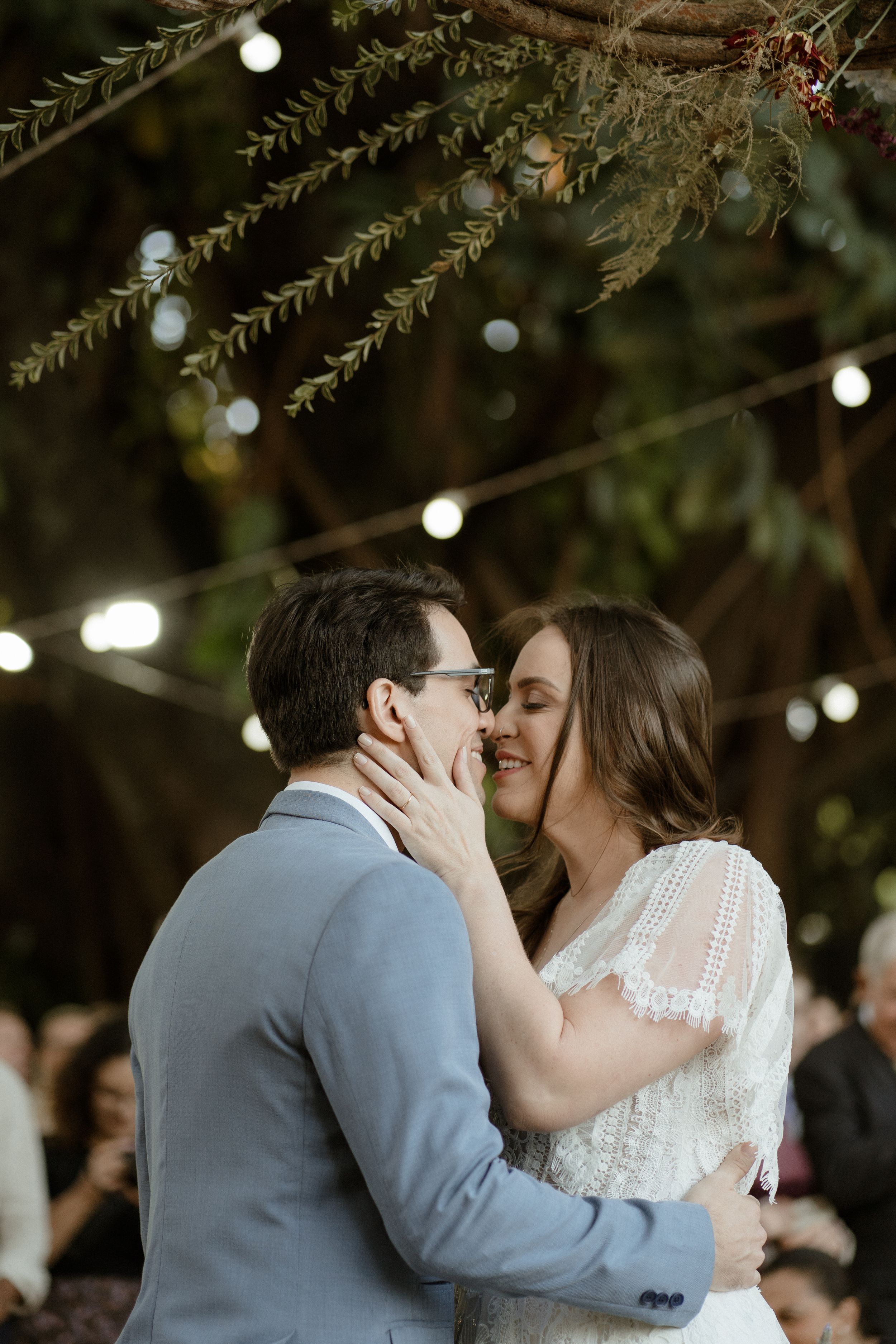 A tender moment captured between newlyweds under string lights at dusk.