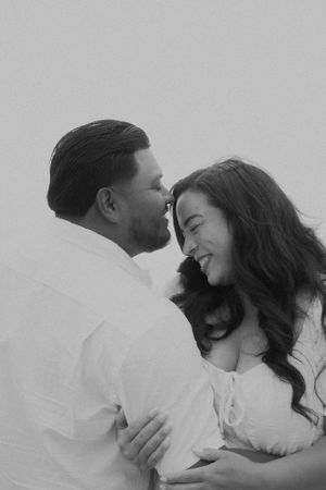 Black and white intimate portraits of couple sharing tender moments during maternity shoot.