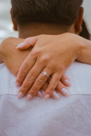 Close-up of hands giving a massage on someone's back while wearing an engagement ring.