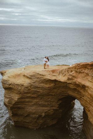 Natural stone arch formation over ocean waters at sunset.