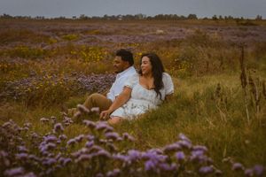 Romantic photoshoot among purple and yellow wildflowers in a coastal setting.