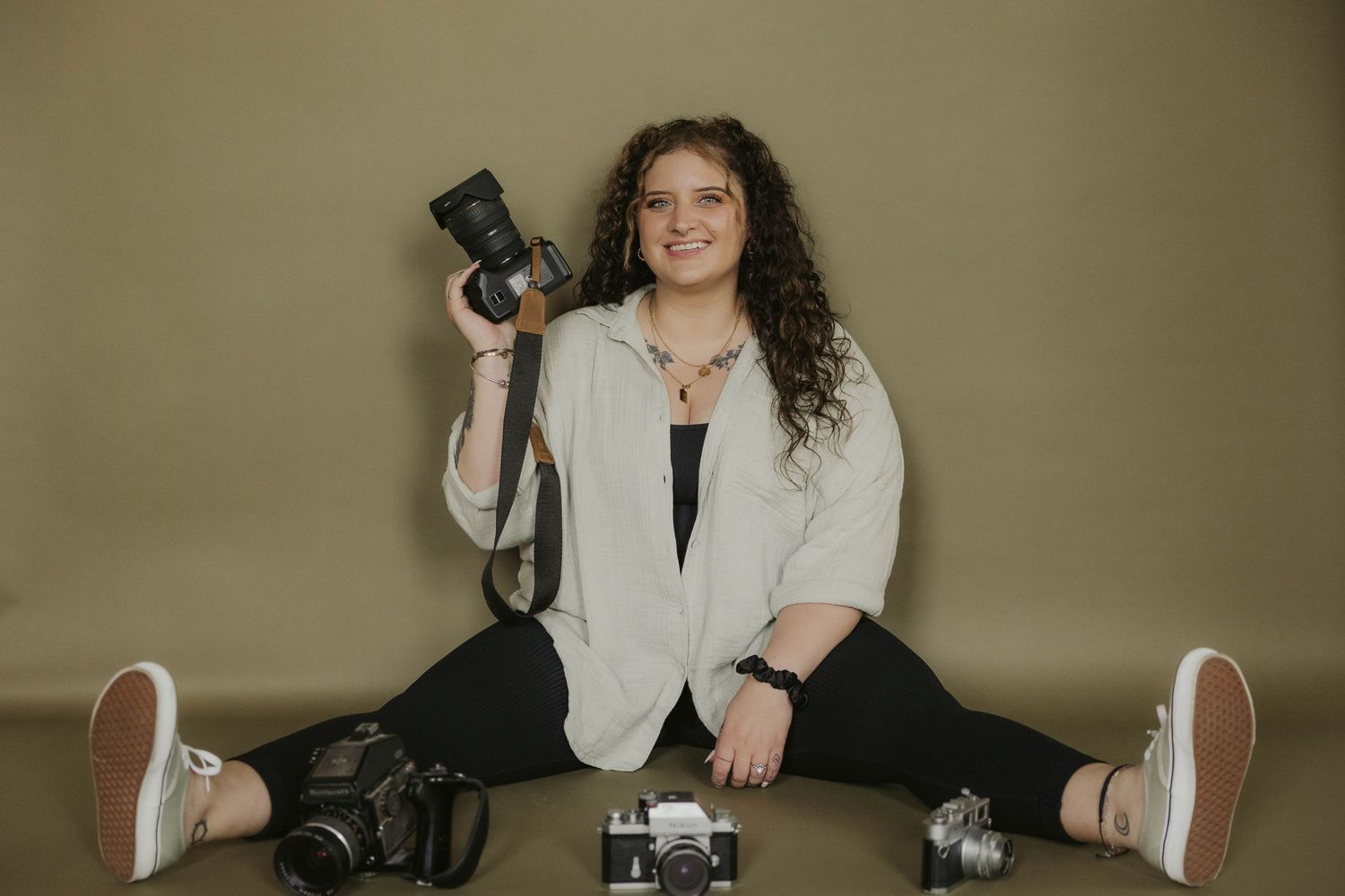 Photographer showcases vintage camera collection in artistic studio portraits.