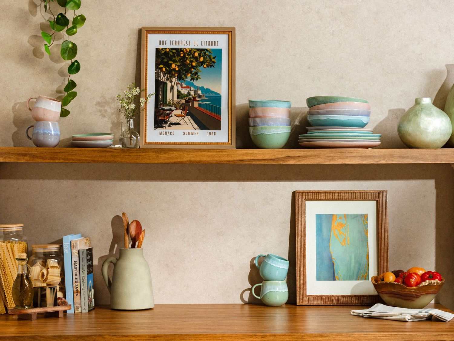Styled product photography of handcrafted ceramic tableware displayed on wooden shelves with framed art, books, and curated home décor.