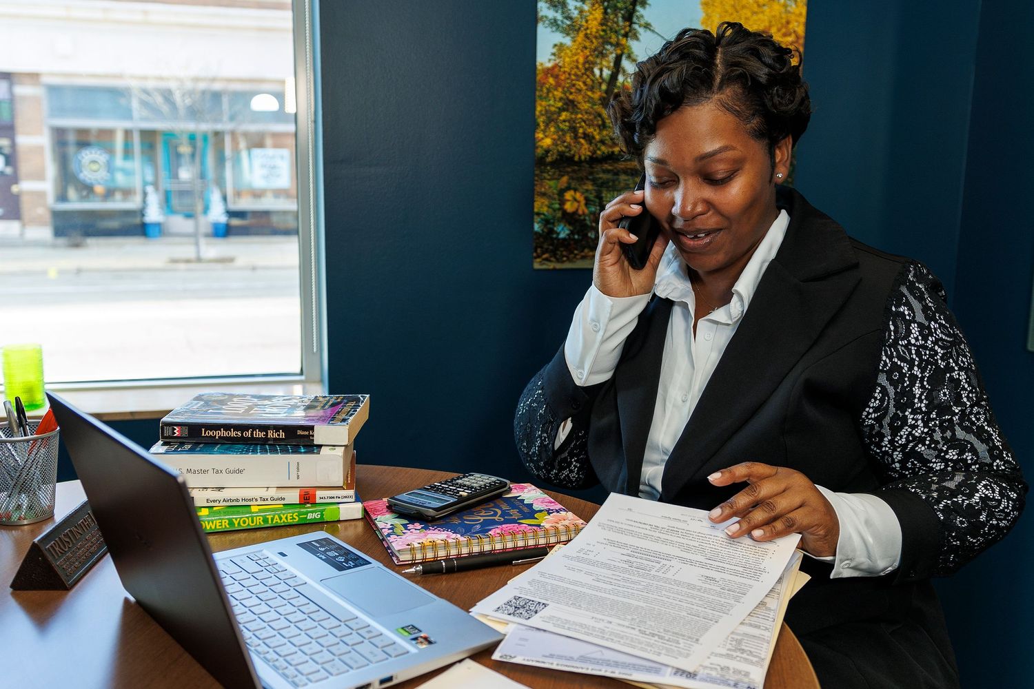 Professional working at desk with laptop and phone in modern office.