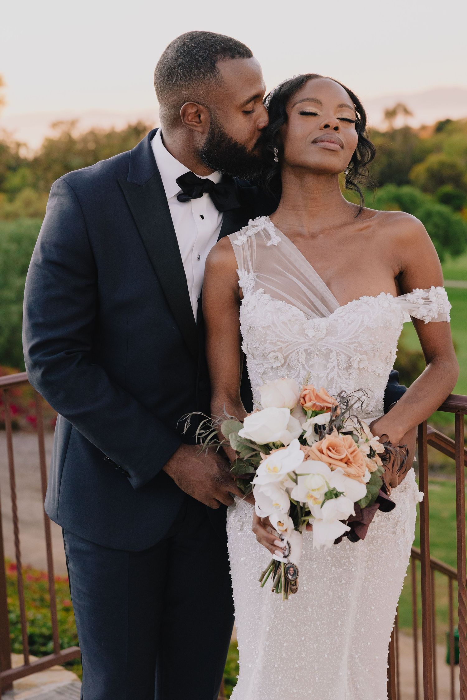 Elegant Black couple on wedding day, bride in beaded gown holding bouquet, groom in black tuxedo.