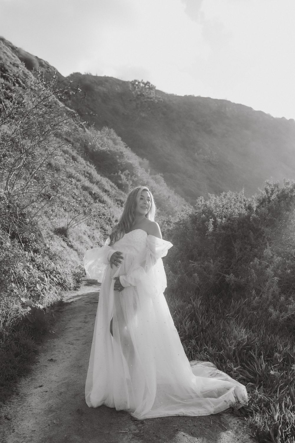Black and white maternity portrait on nature trail with mountains in background.