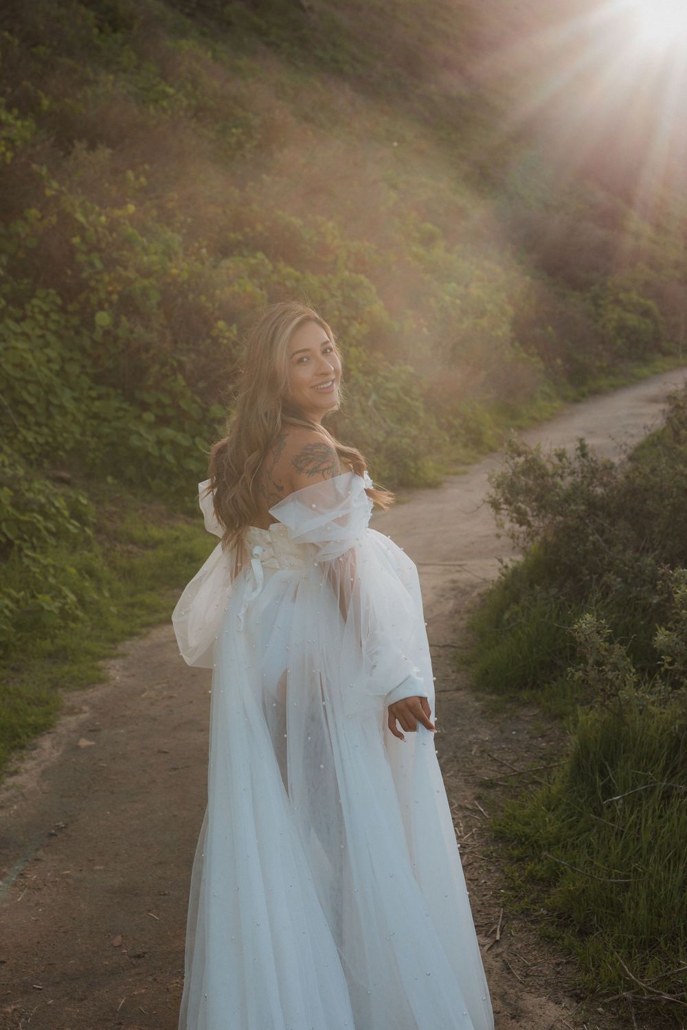 Romantic maternity portrait on nature trail with golden hour lighting.