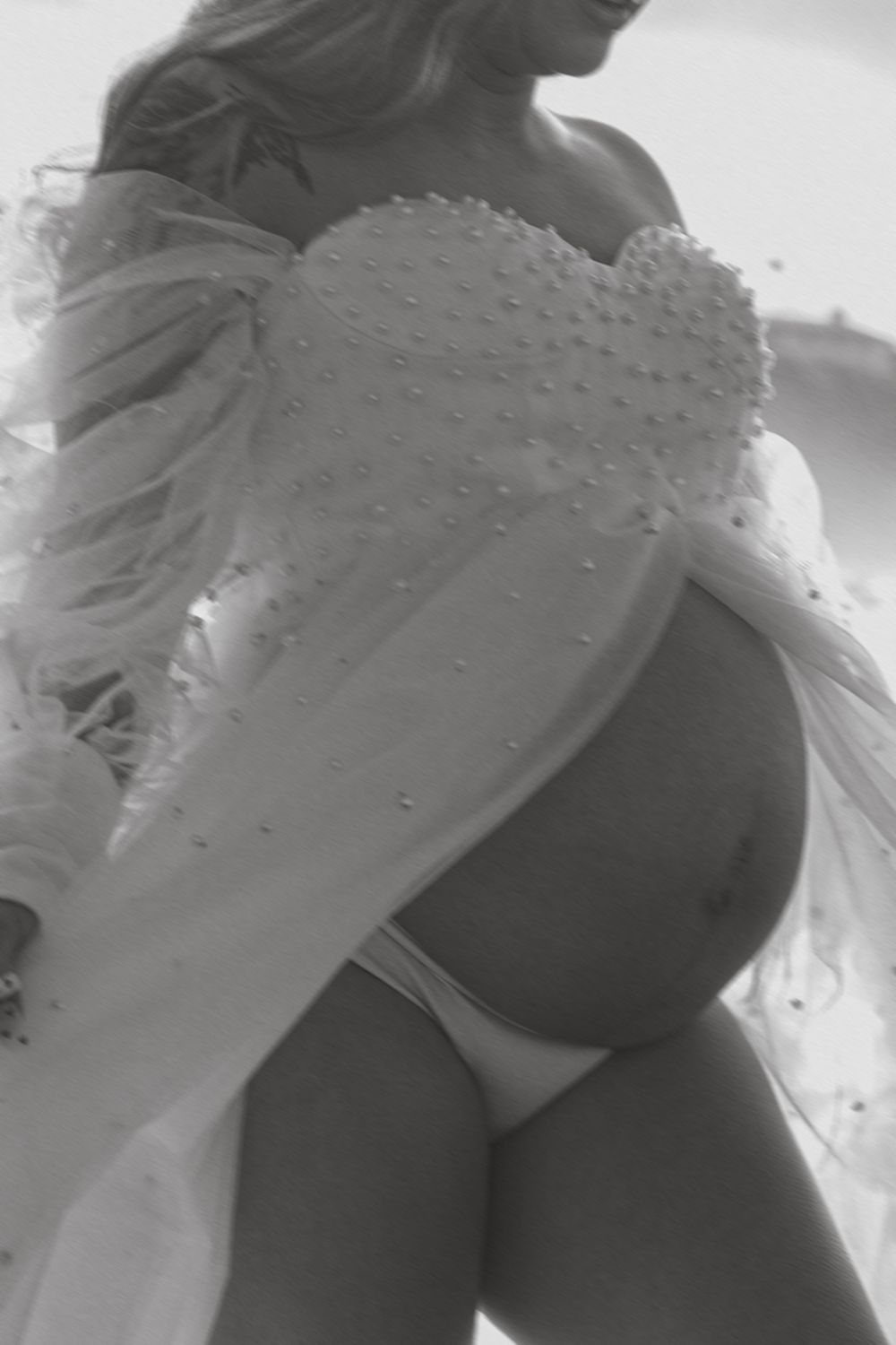Close-up of a white beaded dress detail during a beach maternity photoshoot.