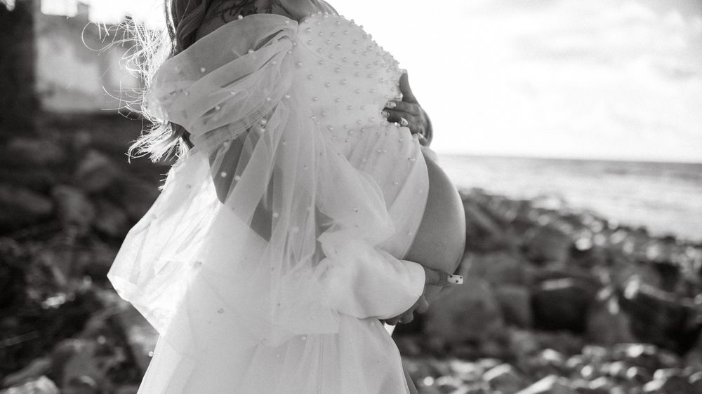 Ethereal black and white photo of flowing white fabric against a rocky coastal backdrop.