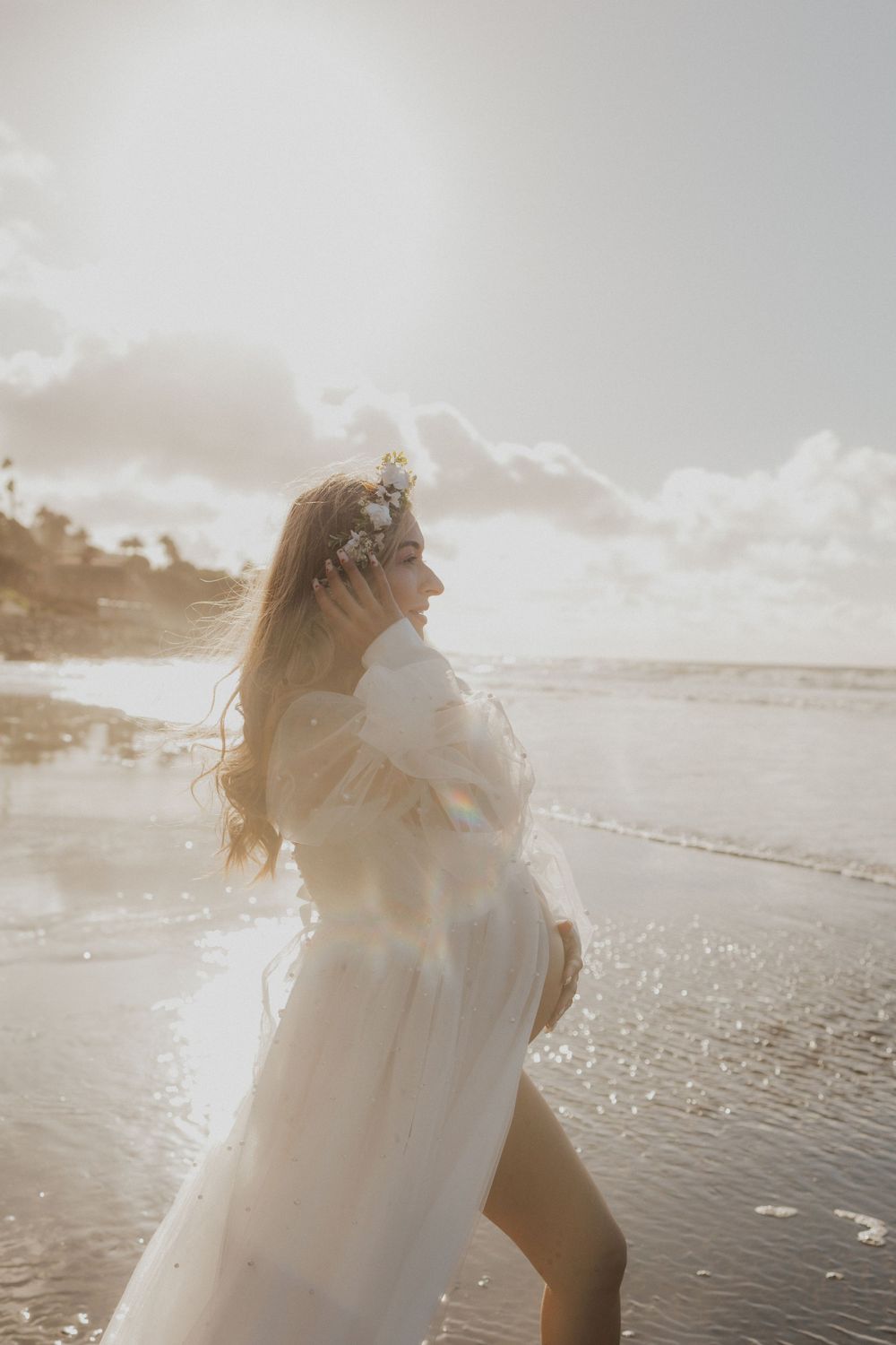 A joyful moment captured during a beachside maternity photoshoot at golden hour.