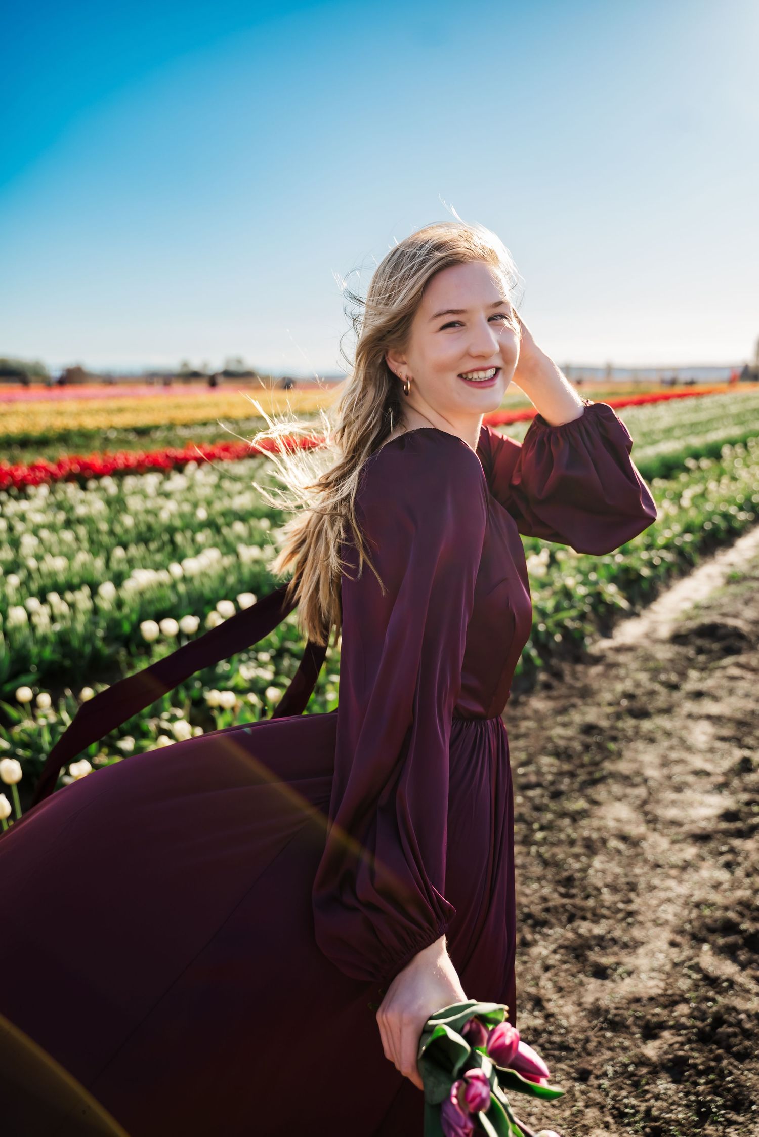 junior girl poses at tulip town in fields in skagit for senior photos